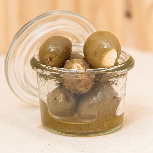 Découvrez nos olives vertes aux amandes. Parfaites pour égayer vos apéritifs, cette combinaison unique offre une expérience gustative équilibrée, où le croquant des amandes se marie harmonieusement à la saveur des olives.