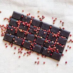 Savourez notre tablette 75% baies roses, une création audacieuse qui marie l’intensité du cacao cru aux notes poivrées et légèrement sucrées des baies roses. Chaque carré est fabriqué avec des fèves de cacao Nacional, réputées pour leurs arômes floraux et fruités exceptionnels. Qui sont soigneusement transformées pour créer un chocolat à la fois riche et raffiné. L’ajout de baies roses broyées apporte une dimension épicée et subtilement sucrée. Equilibrant merveilleusement l’amertume du cacao avec une explosion de saveurs vibrantes. Cette tablette offre une expérience gustative complexe. Alliant le caractère intense du chocolat noir à la fraîcheur épicée des baies roses. Que ce soit pour un moment de dégustation contemplatif ou comme une touche sophistiquée à votre pause gourmande. Notre tablette 75% baies roses vous invite à explorer une fusion délicate et savoureuse de chocolat et d’épices.